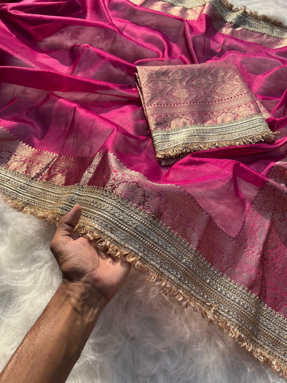 Pink saree with gold border and a hand holding it